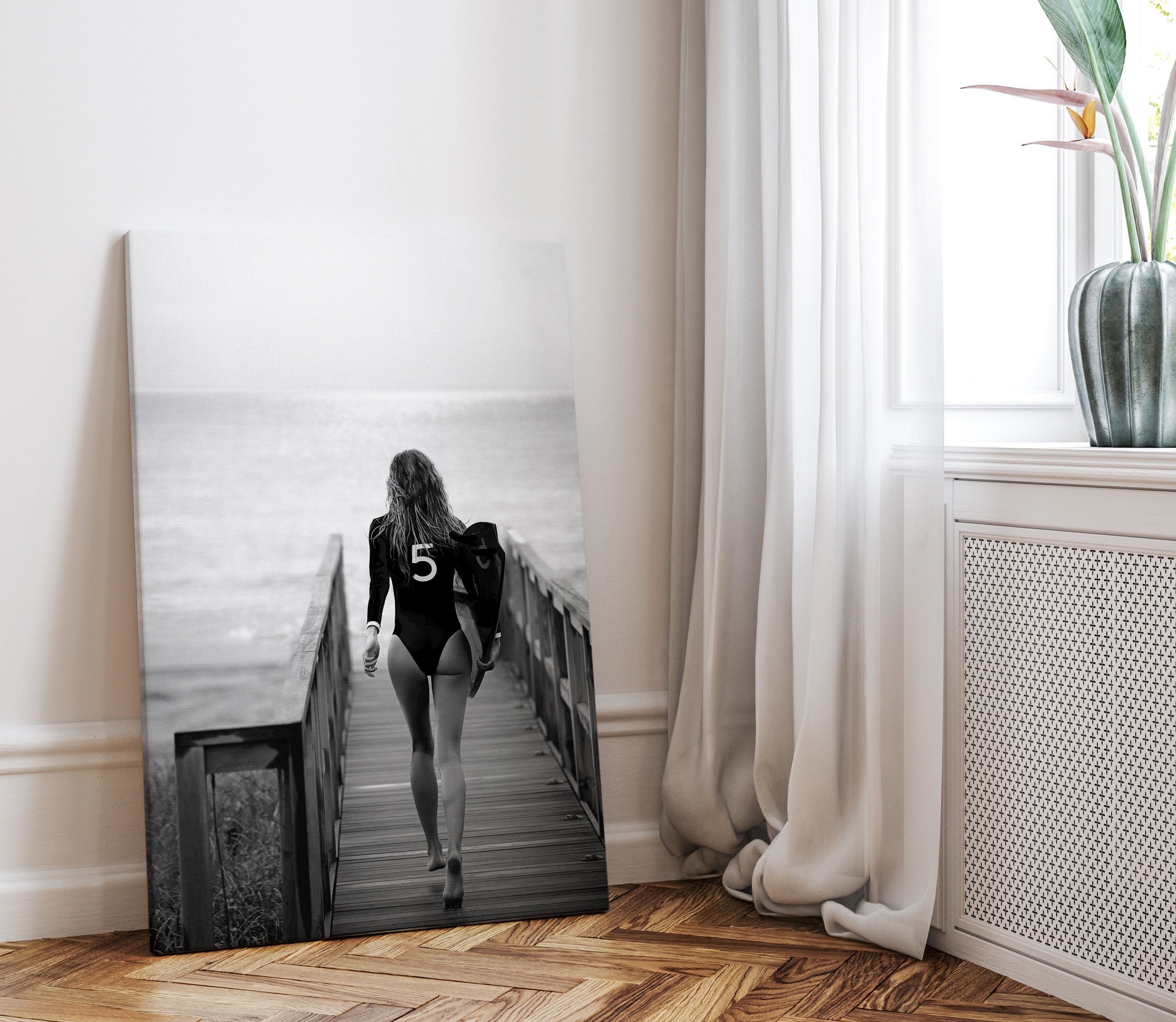 black and white canvas print of a woman in bathing suit ready to go surfing. ther eis a print of the coco chanel nr 5 on the bathing suit