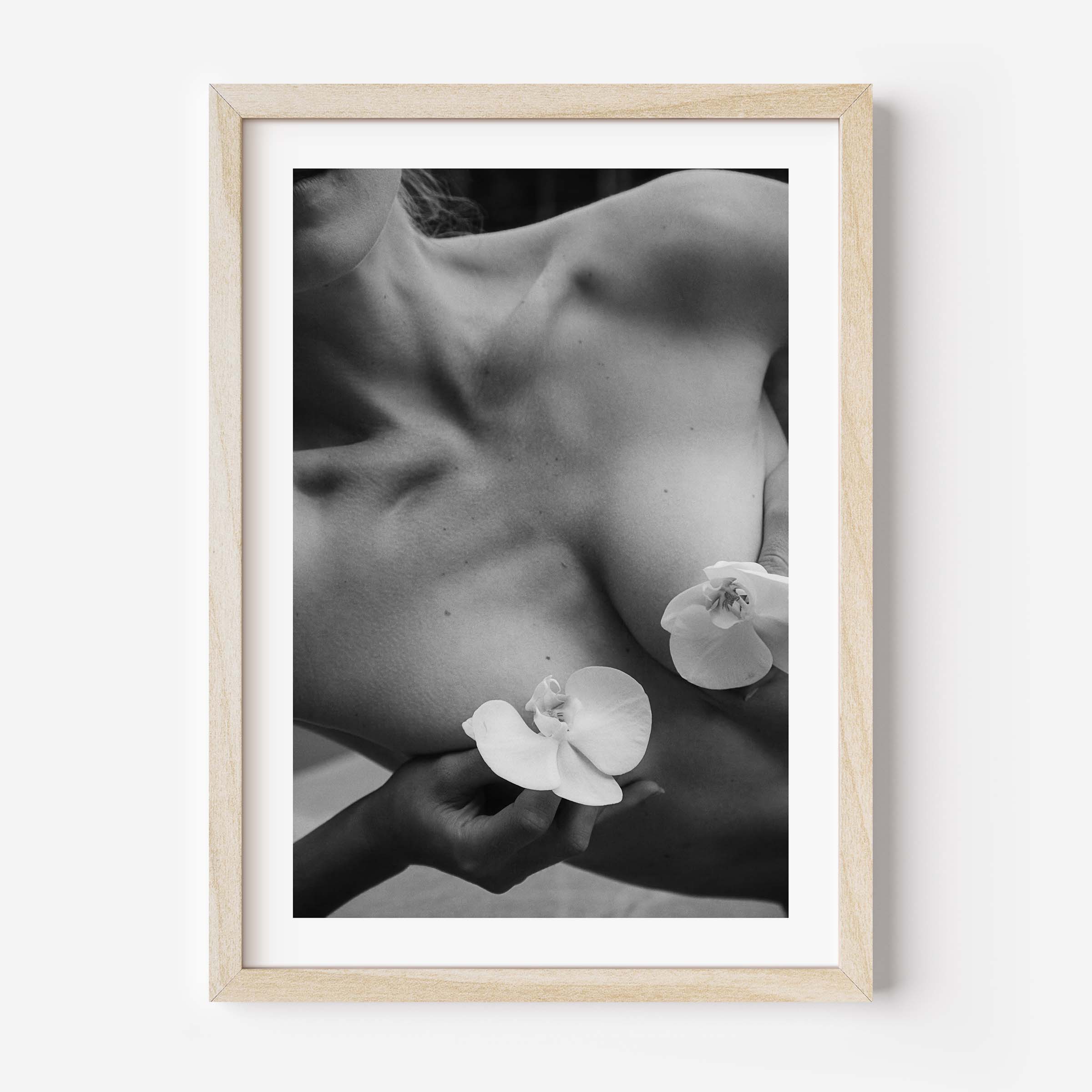 Framed black-and-white photograph of a woman’s collarbone with white orchid flowers, styled in a Parisian interior with molding, mirror, and chair — by Britt Van der Meijden.