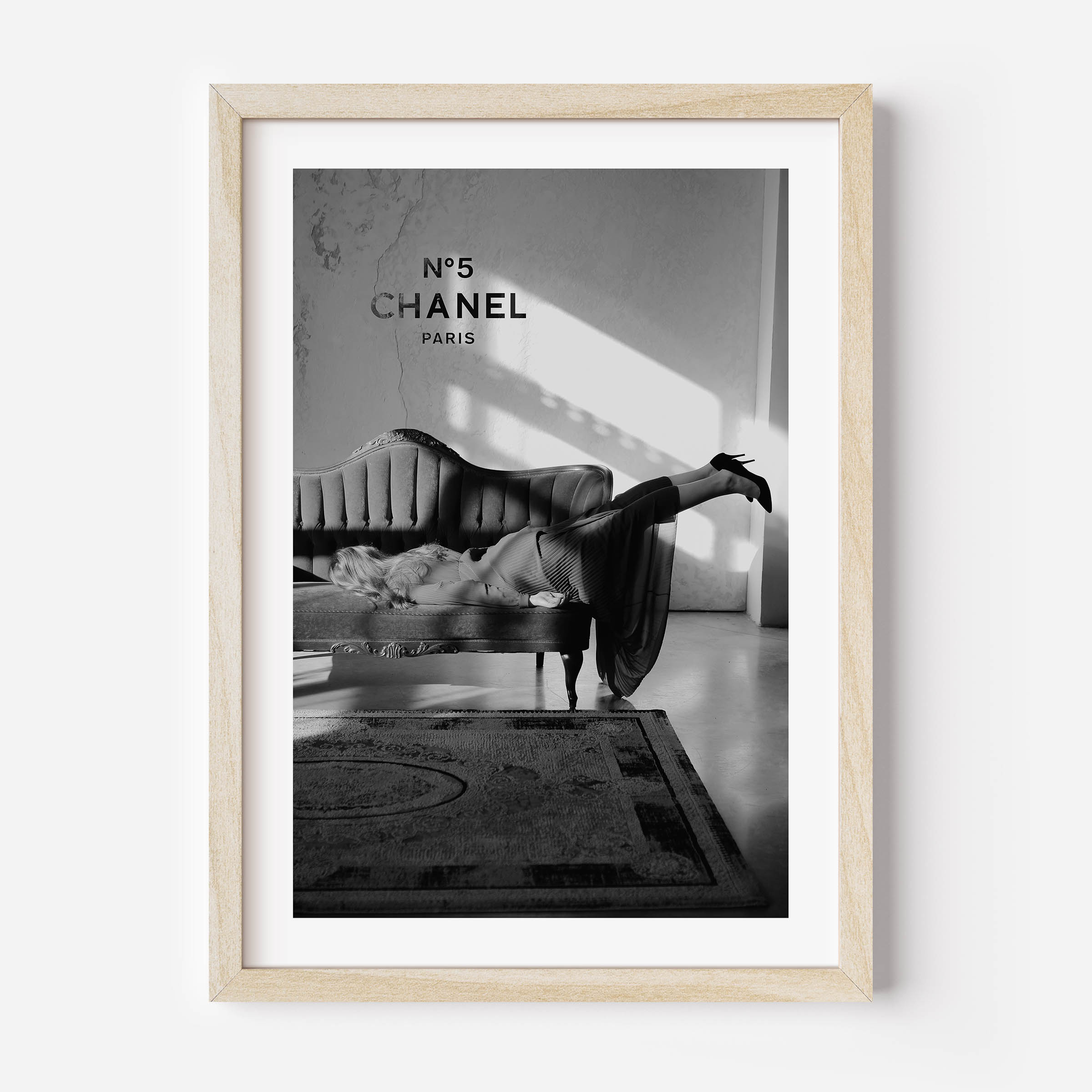 black and white poster of a woman on a sofa with in the background chanel n5 on the wall