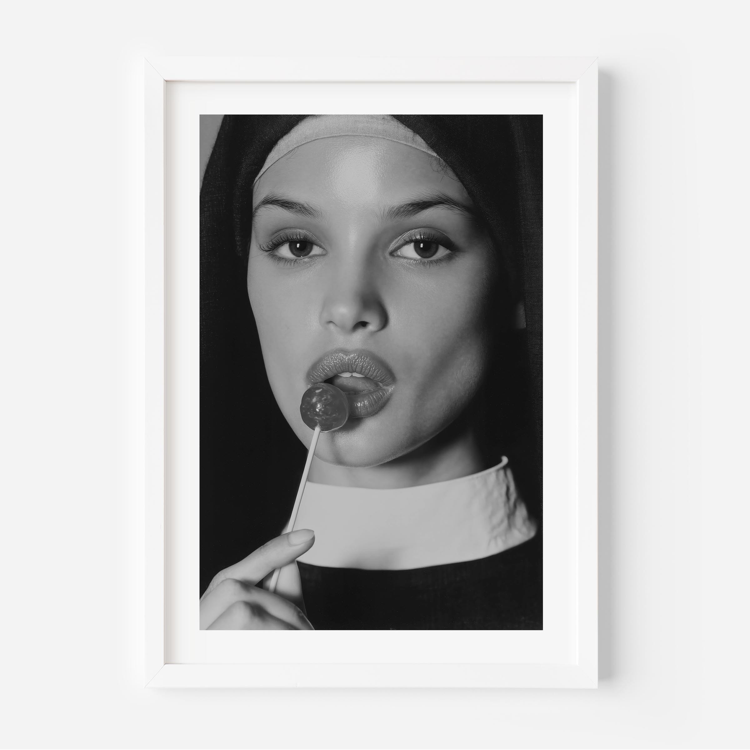 Black-and-white fine art photograph of a woman dressed as a nun, sensually holding a lollipop to her lips.