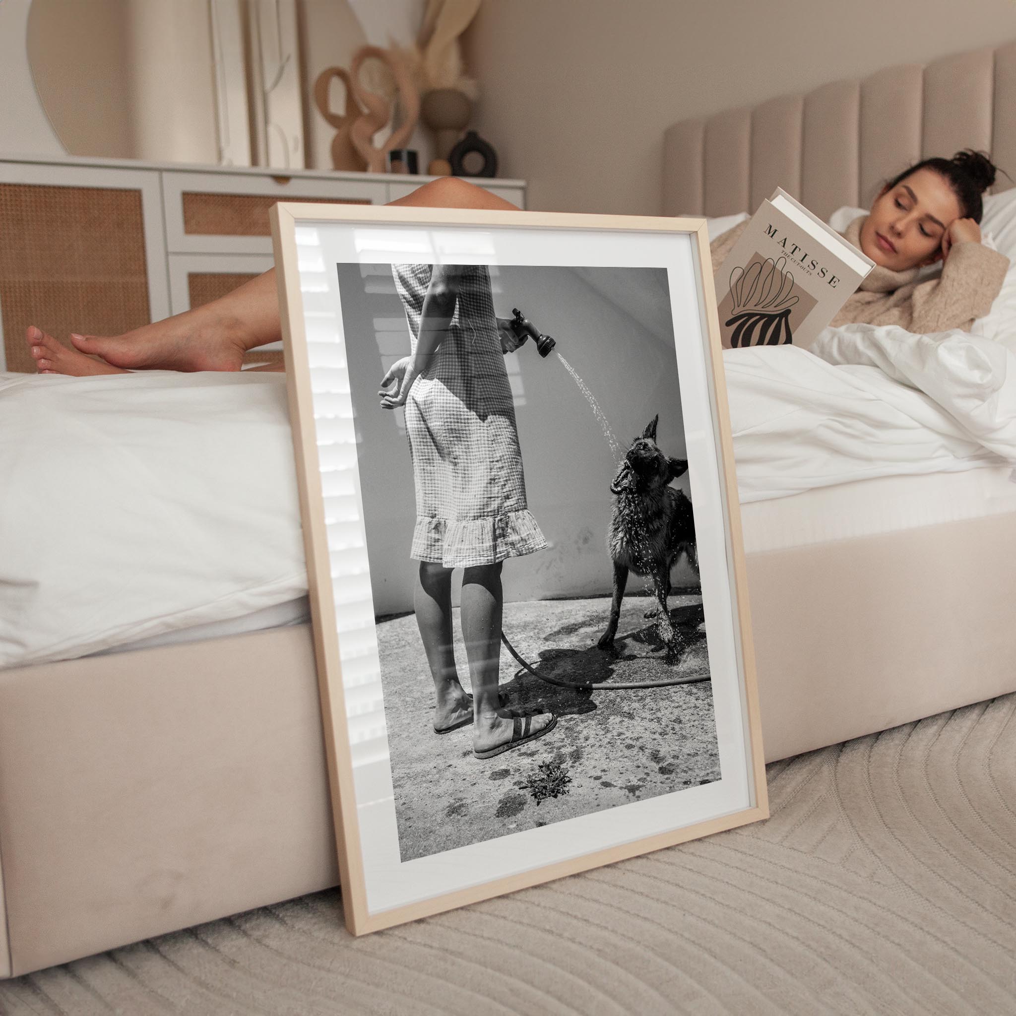 black and white fine art print depicting a woman spraying water into a dog's mouth. The scene captures a tranquil, intimate moment, evoking the charm of slow mornings in Italy. The minimalist composition is perfect for home decor and wall art, adding a timeless touch to any interior design.