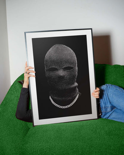 Black-and-white portrait of a person in a knit balaclava with eye cutouts and a silver chain on a solid black background, minimalist fine art print.