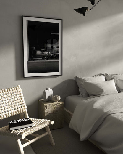Black-and-white fine art photo of a luxury SUV parked inside an aircraft hangar with a private jet in the background.