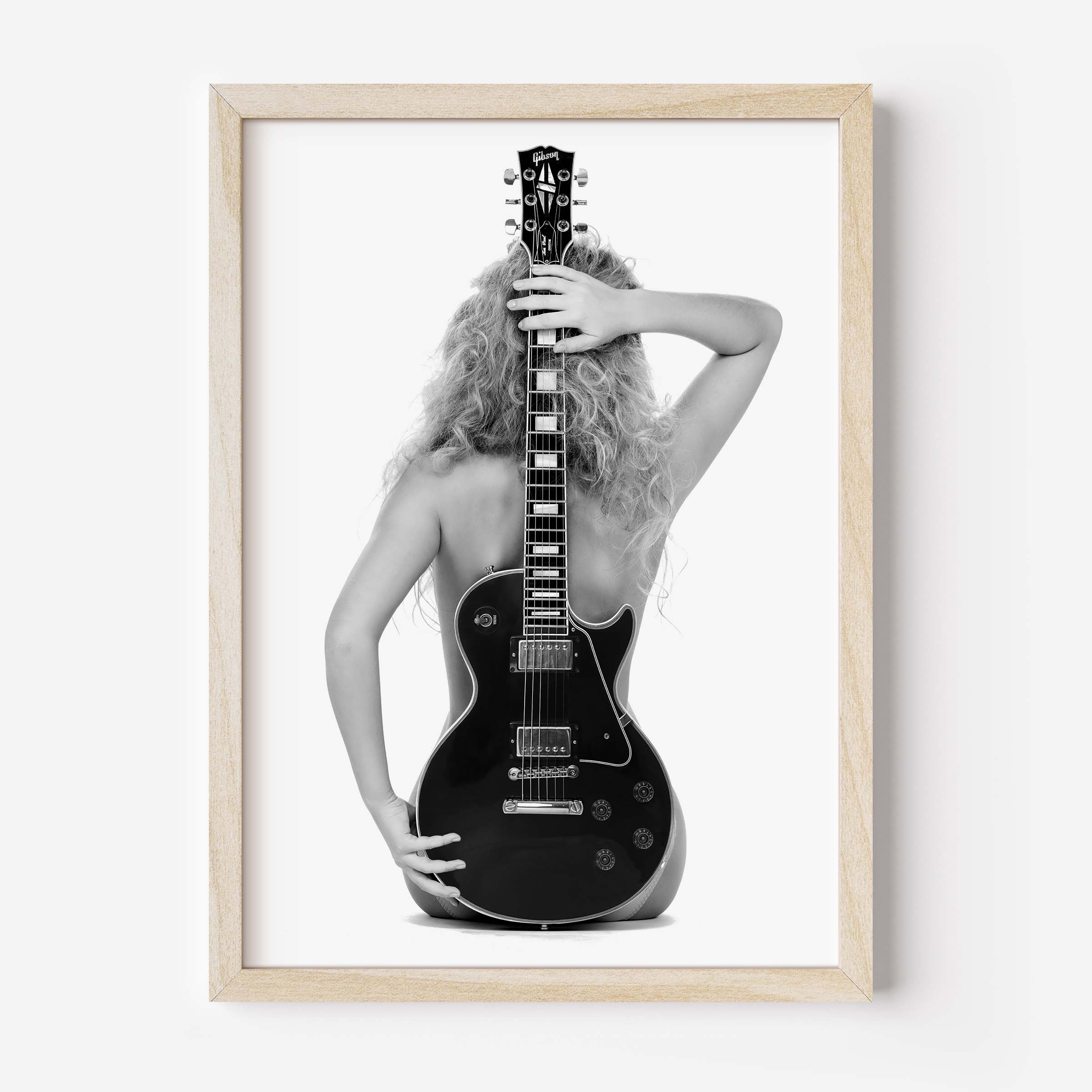 Black-and-white fine art print of a figure from behind holding an electric guitar on a white background.