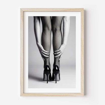 Framed black and white art print of legs wearing fishnet stockings and high heels on a gray background.