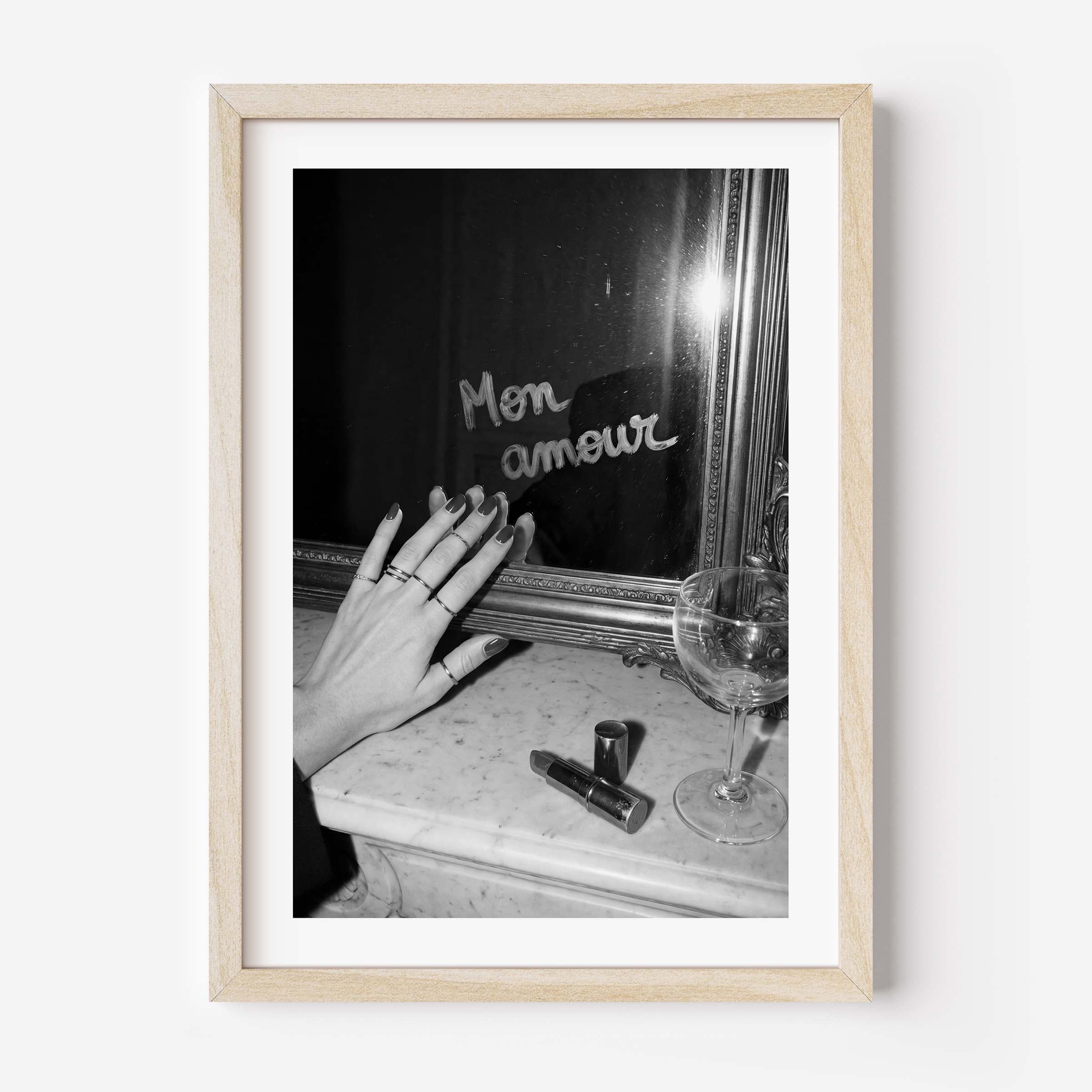 Framed black and white photo of a hand with rings near a mirror and glass.