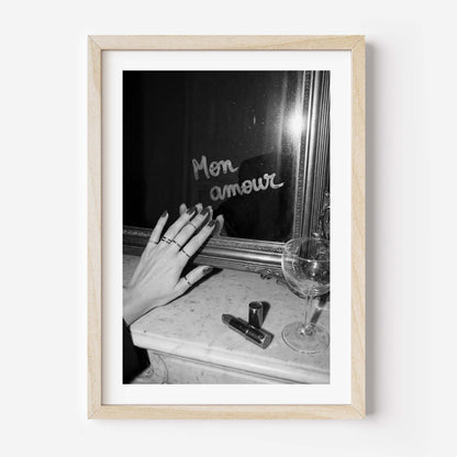 Framed black and white photo of a hand with rings near a mirror and glass.
