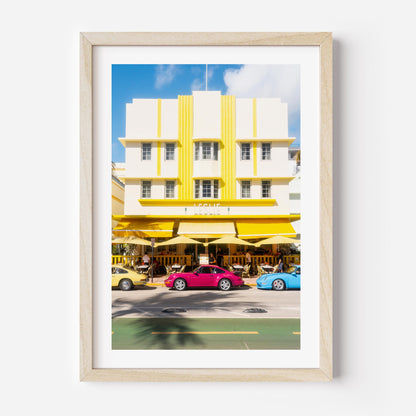 Fine art wall print of a colorful Miami street with Art Deco building and classic cars, evoking nostalgic summer road trip vibes.