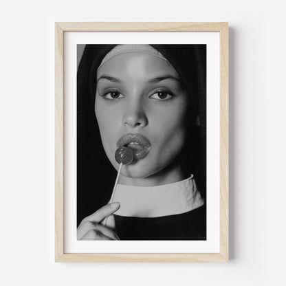 Black-and-white fine art photograph of a woman dressed as a nun, sensually holding a lollipop to her lips.