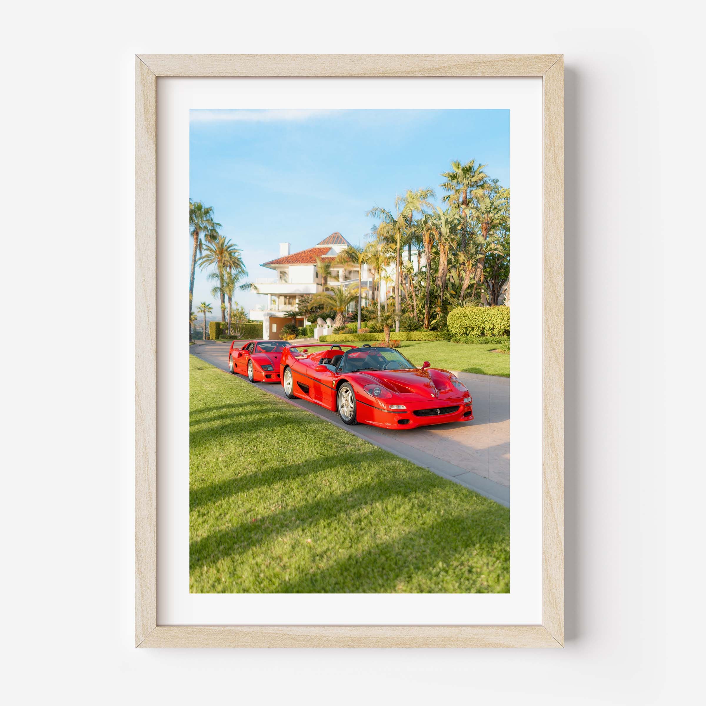 Framed fine art print of three red Italian supercars parked by a palm-lined villa on a sunny day, luxury driveway scene.