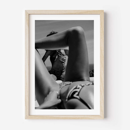 Black-and-white photo of two women relaxing poolside; foreground legs frame a seated figure in a zebra-print top, by Britt van der Meijden