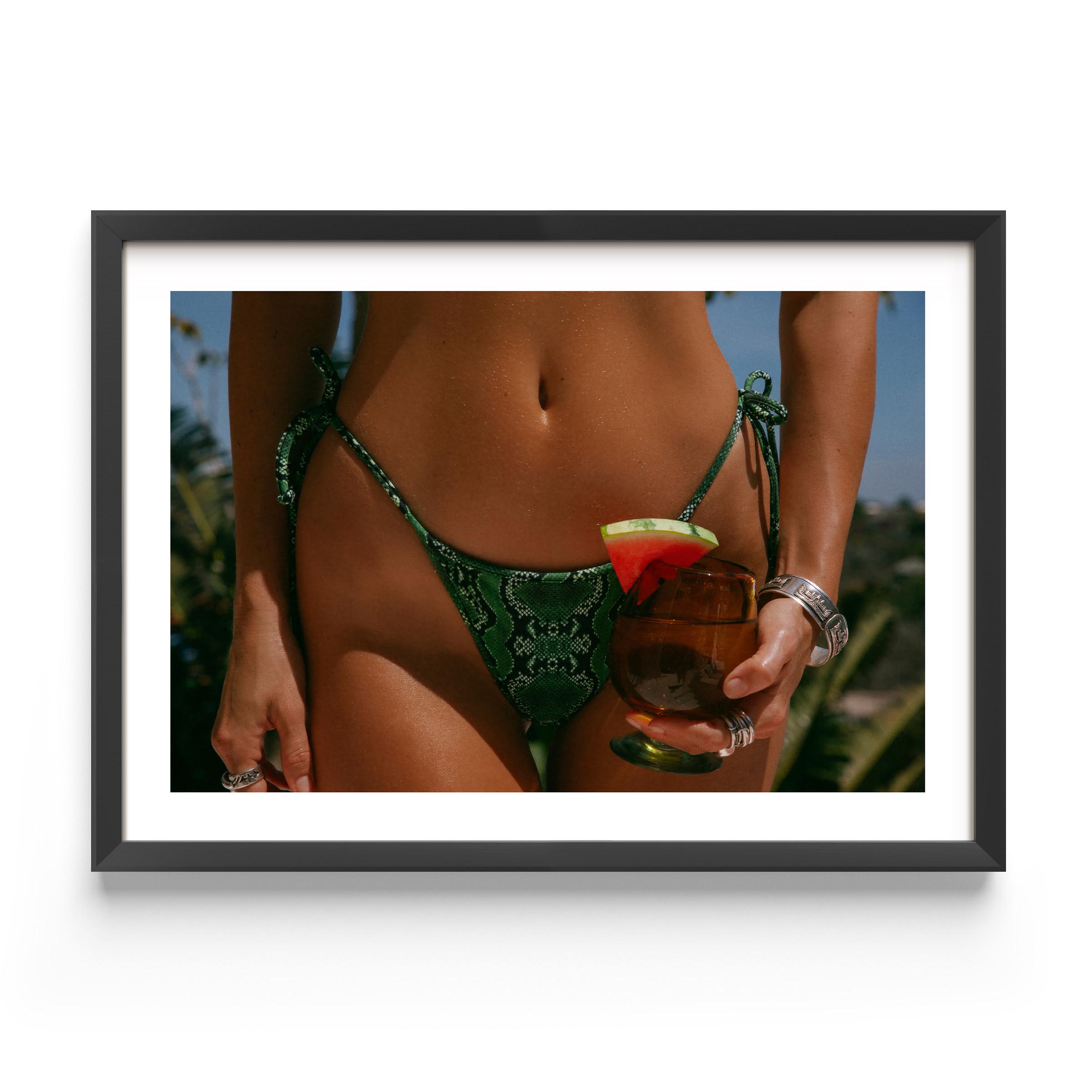 Framed fine-art photograph of a woman in an emerald snakeskin bikini holding a cocktail with a watermelon garnish; summer fashion editorial by Britt Van der Meyden.