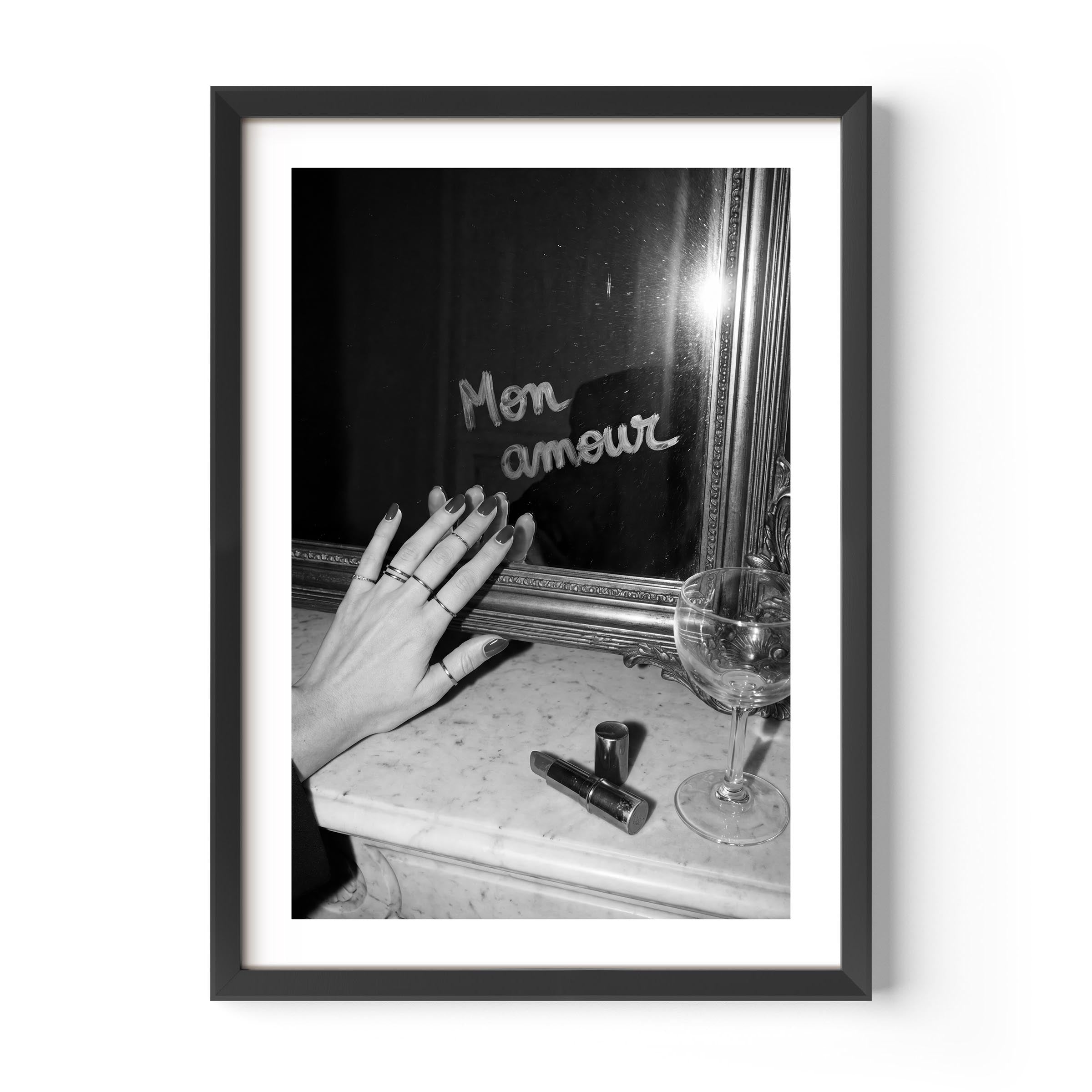 Framed black and white photo of a hand with rings near a mirror reflecting 'Mon amour'.