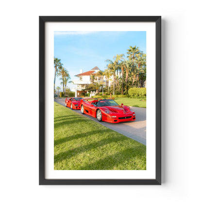 Framed fine art print of three red Italian supercars parked by a palm-lined villa on a sunny day, luxury driveway scene.