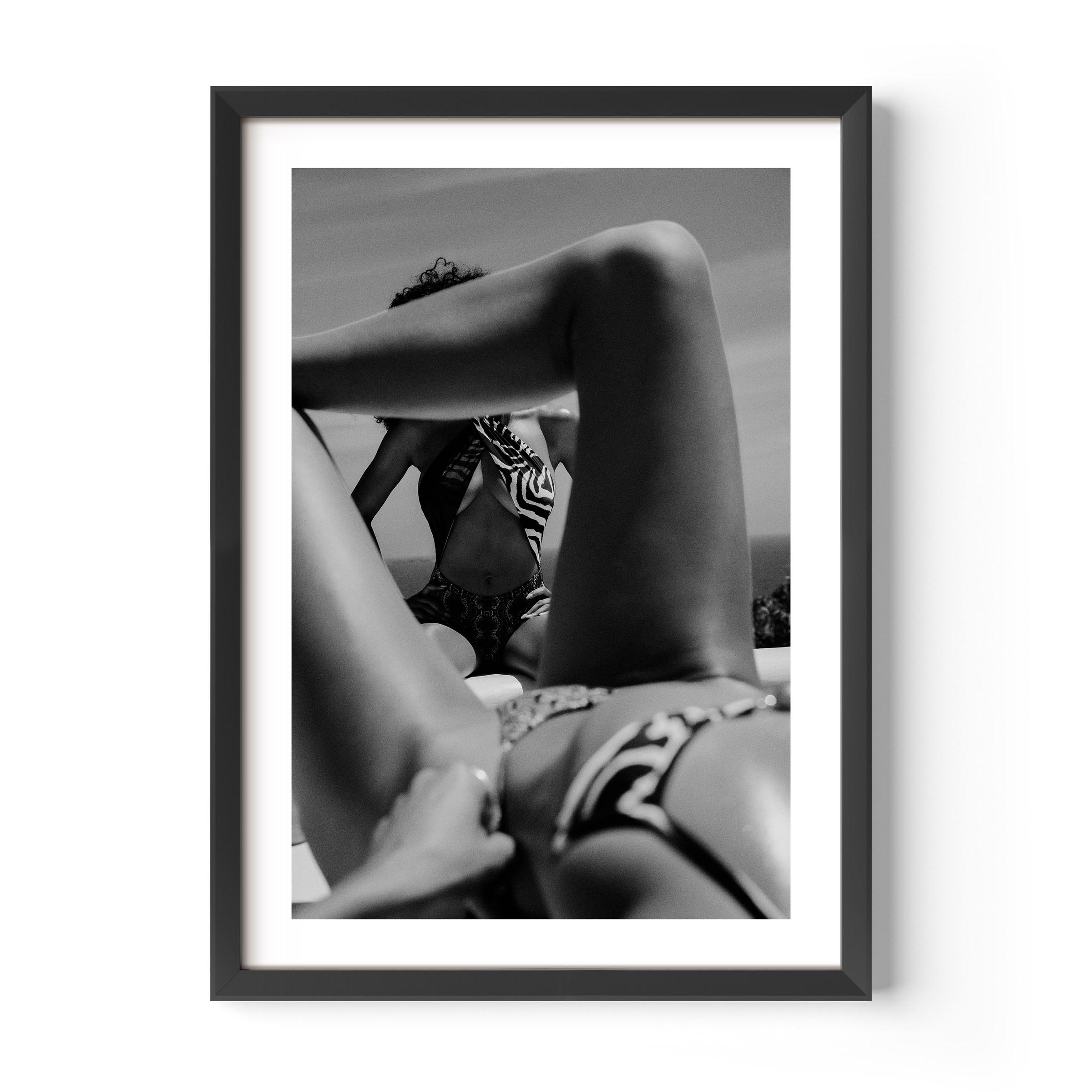 Black-and-white photo of two women relaxing poolside; foreground legs frame a seated figure in a zebra-print top, by Britt van der Meijden