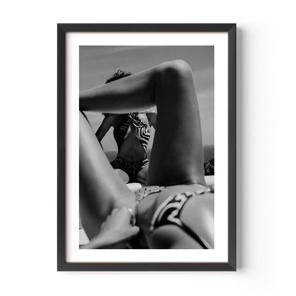 Black-and-white photo of two women relaxing poolside; foreground legs frame a seated figure in a zebra-print top, by Britt van der Meijden