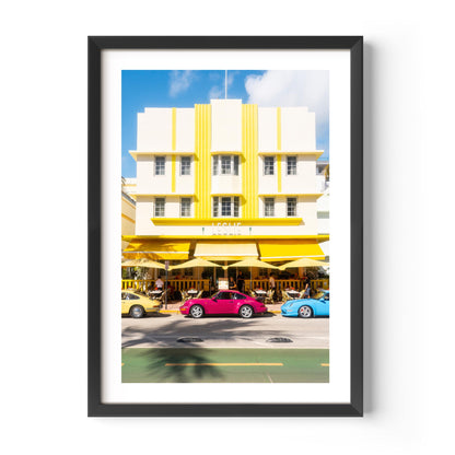Fine art wall print of a colorful Miami street with Art Deco building and classic cars, evoking nostalgic summer road trip vibes.