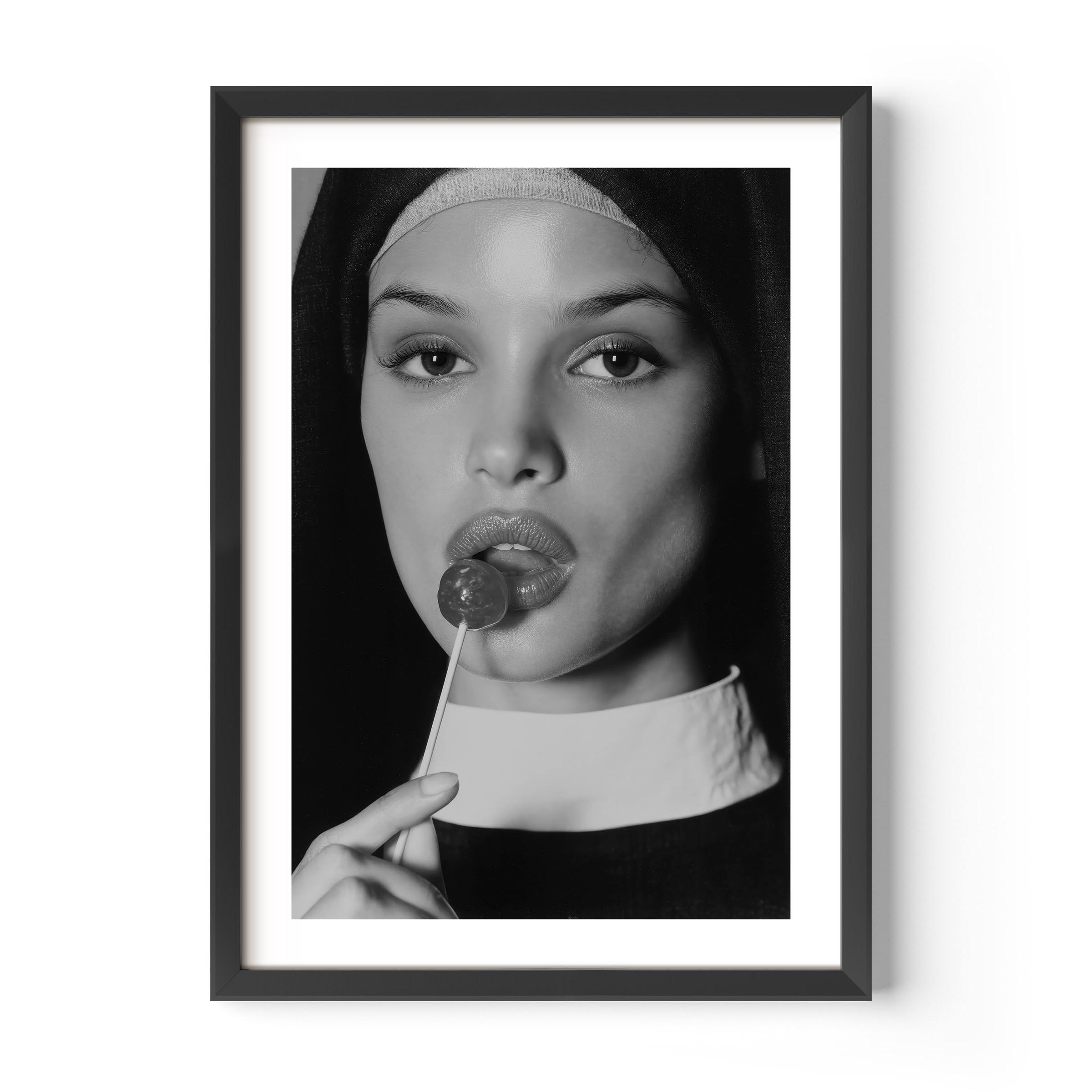 Black-and-white fine art photograph of a woman dressed as a nun, sensually holding a lollipop to her lips.
