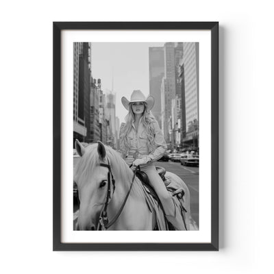 Black and white fine art photograph of a woman elegantly riding a horse through the streets of New York City, captured on analog film. The image exudes timeless sophistication, blending urban energy with classic equestrian grace