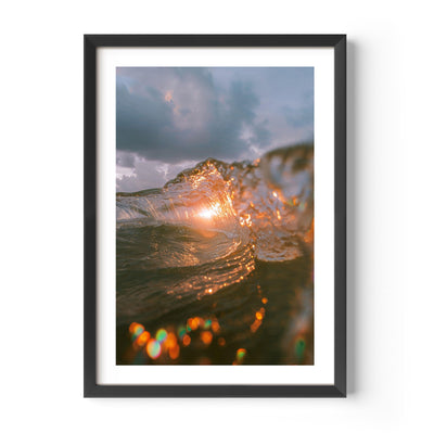 A fine art print of a wave crashing with the sun setting behind it, casting a golden glow on the water. The dynamic motion of the wave is beautifully captured, evoking a sense of energy and tranquility. Ideal for ocean and nature lovers.