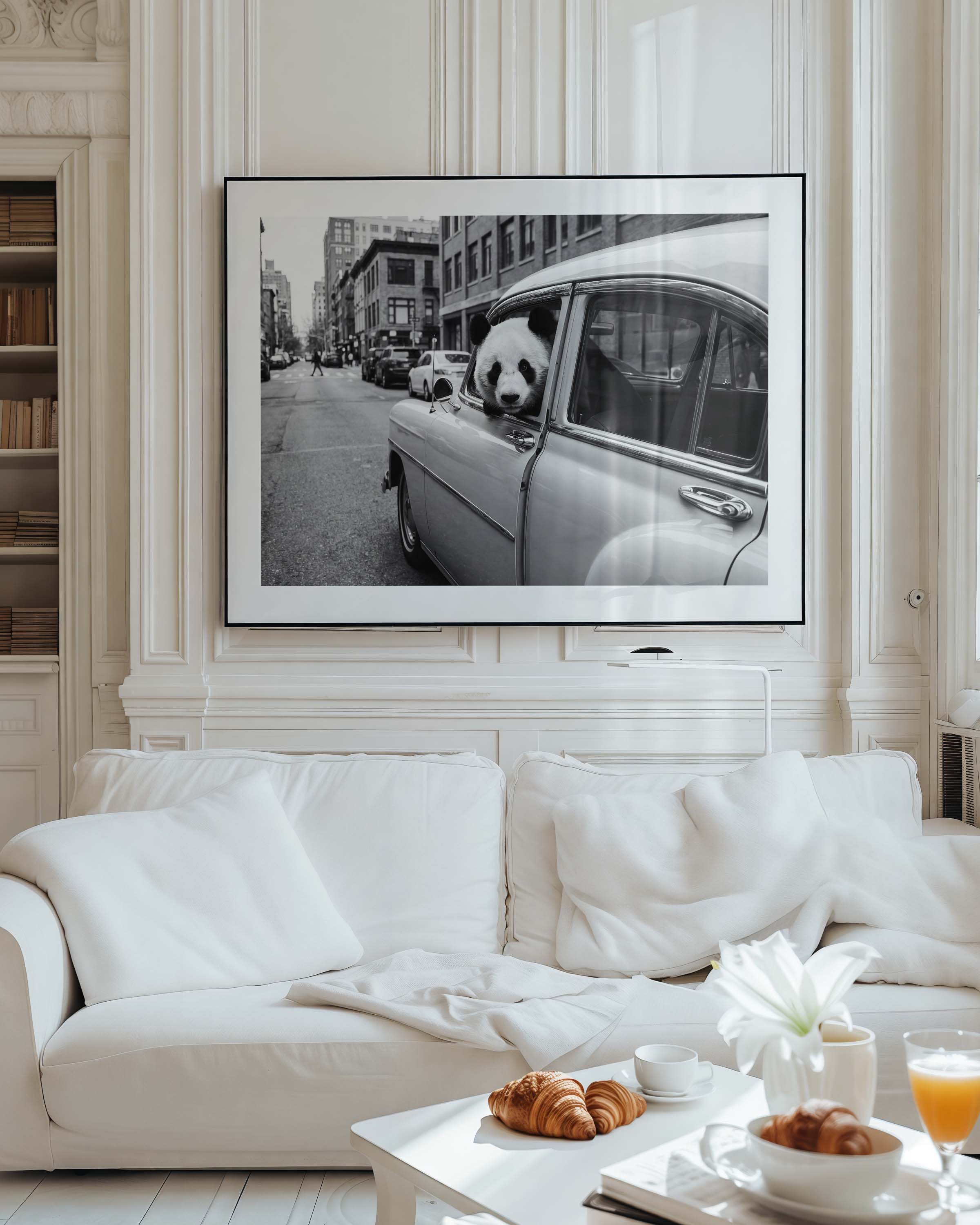 Framed black and white art print of a giant panda leaning out of a vintage classic car window on a busy city street, with urban buildings in the background. White mat border in a black frame, printed on premium 230g matte paper.