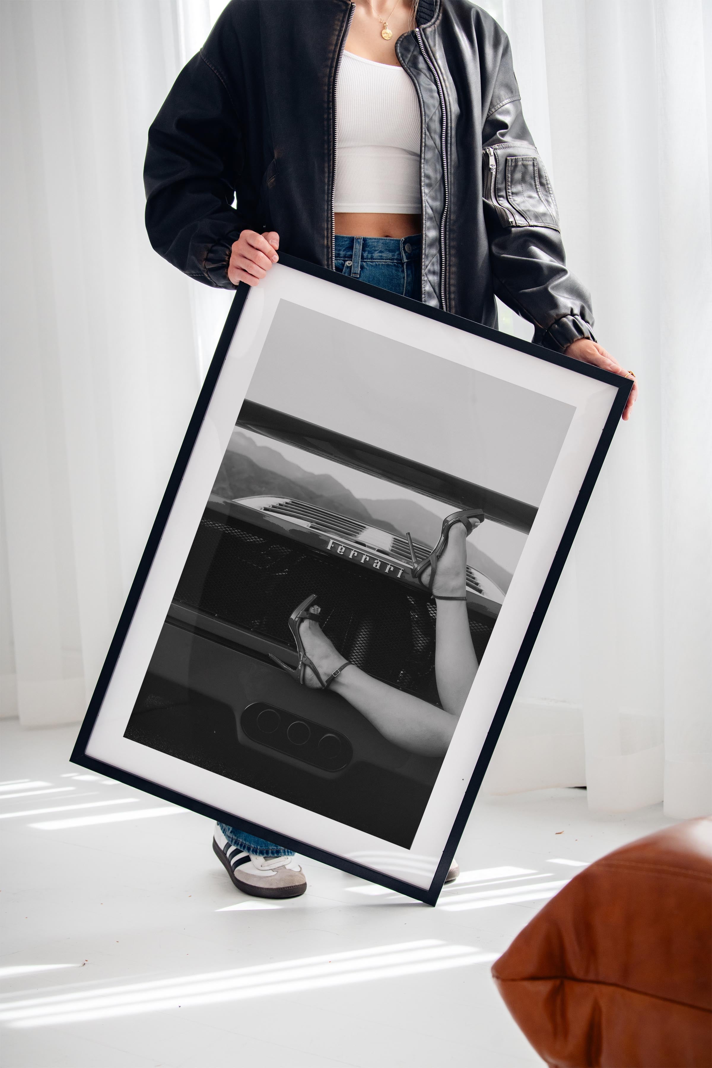 Black-and-white fine art print of high heels resting on the back of a Ferrari, framed wall art.