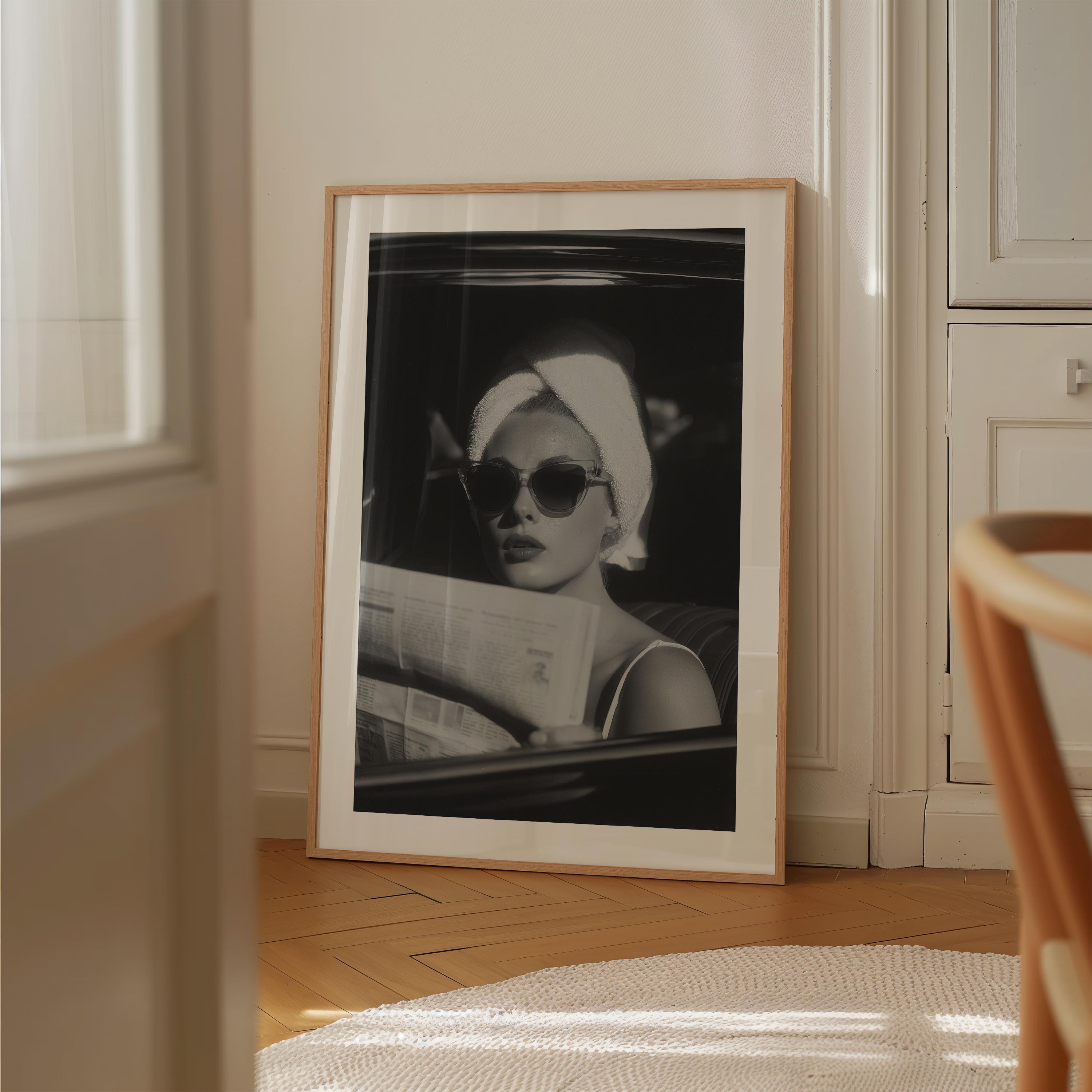 Channel vintage glamour with this black-and-white fine art print of a chic woman in sunglasses reading the paper. Perfect for stylish, fashion-inspired interiors.