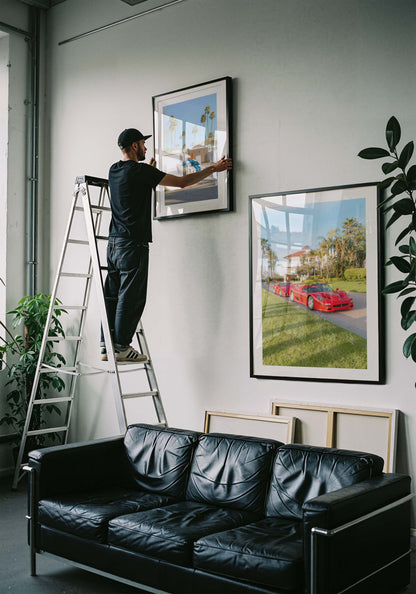 Framed fine art print of three red Italian supercars parked by a palm-lined villa on a sunny day, luxury driveway scene.
