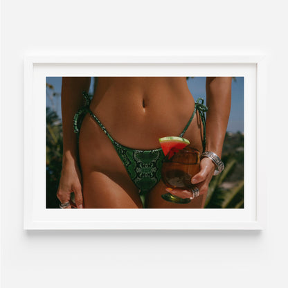 Framed fine-art photograph of a woman in an emerald snakeskin bikini holding a cocktail with a watermelon garnish; summer fashion editorial by Britt Van der Meyden.