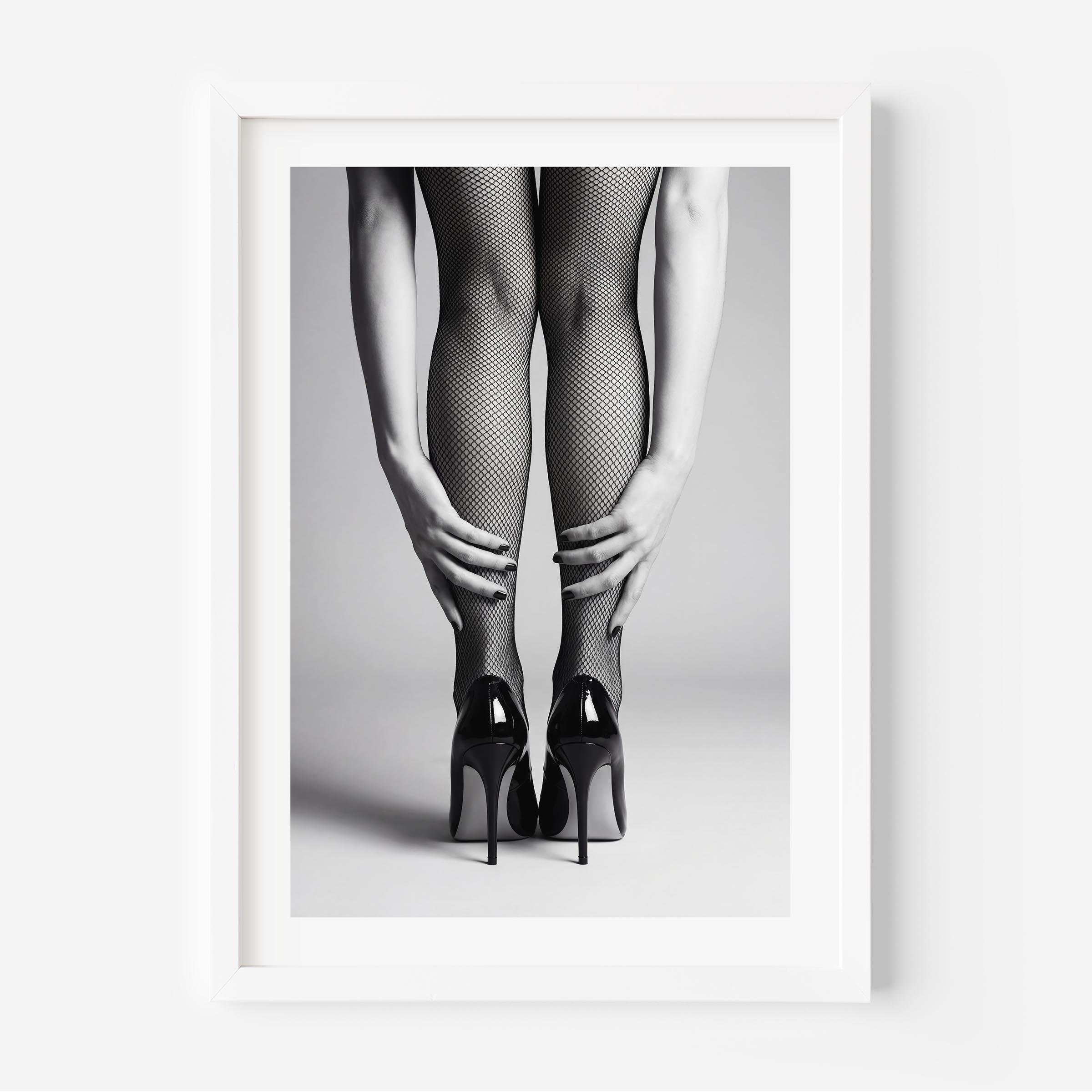 Framed black and white art print of legs wearing fishnet stockings and high heels on a gray background.