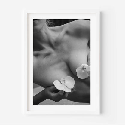 Framed black-and-white photograph of a woman’s collarbone with white orchid flowers, styled in a Parisian interior with molding, mirror, and chair — by Britt Van der Meijden.