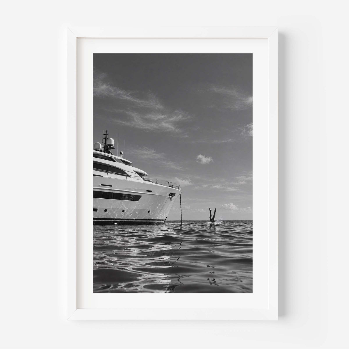 A framed black and white art print depicting a luxury yacht on the ocean, with a person standing in the water nearby, shown against a clean white background.