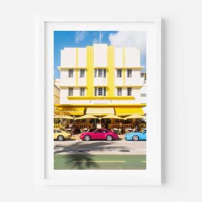 Fine art wall print of a colorful Miami street with Art Deco building and classic cars, evoking nostalgic summer road trip vibes.