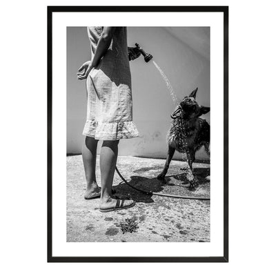  black and white fine art print depicting a woman spraying water into a dog's mouth. The scene captures a tranquil, intimate moment, evoking the charm of slow mornings in Italy. The minimalist composition is perfect for home decor and wall art, adding a timeless touch to any interior design.