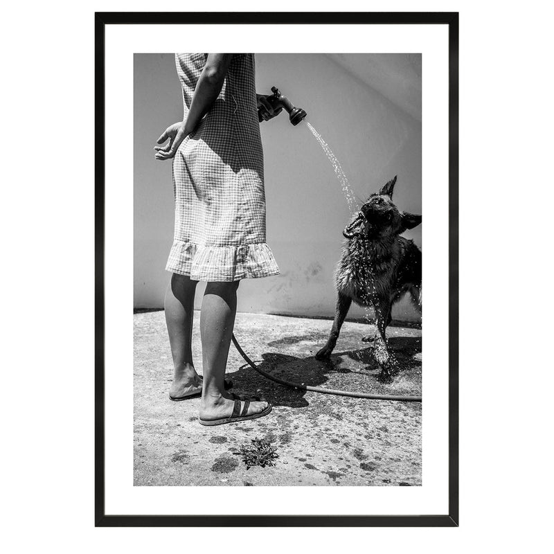  black and white fine art print depicting a woman spraying water into a dog&