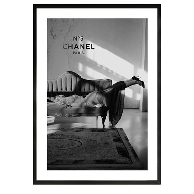 black and white poster of a woman on a sofa with in the background chanel n5 on the wall