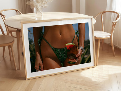Framed fine-art photograph of a woman in an emerald snakeskin bikini holding a cocktail with a watermelon garnish; summer fashion editorial by Britt Van der Meyden.