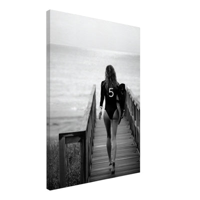 black and white canvas print of a woman in bathing suit ready to go surfing. ther eis a print of the coco chanel nr 5 on the bathing suit